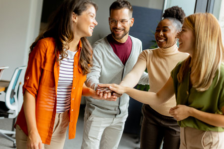 Young multiethnic startup team hold hands togetherat the modern officeの写真素材