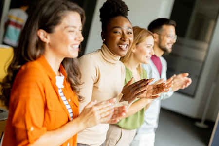Young multiethnic startup team standing and applauding at the modern officeの写真素材
