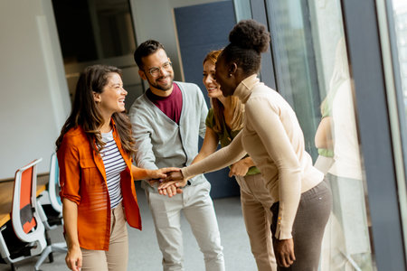 Young multiethnic startup team hold hands togetherat the modern officeの写真素材