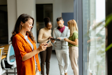 Young business woman woman with mobile phonet in front of her team at the modern officeの写真素材
