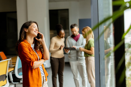 Young business woman woman with mobile phonet in front of her team at the modern officeの写真素材