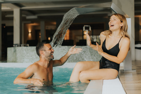 Handsome young couple having fun in the indoor swimming poolの写真素材