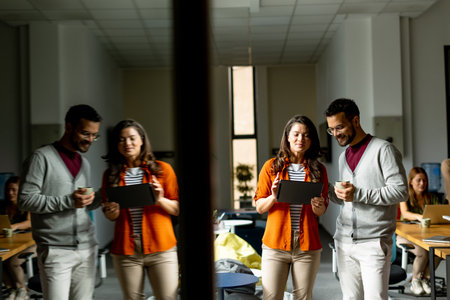 Young business couple standing with digital tablet in front of her team at the modern officeの写真素材