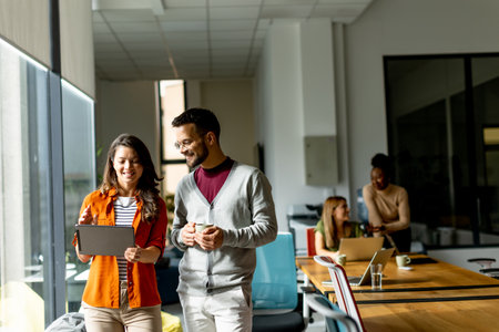 Young business couple standing with digital tablet in front of her team at the modern officeの写真素材