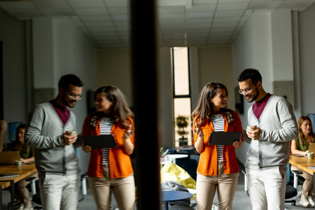 Young business couple standing with digital tablet in front of her team at the modern officeの写真素材