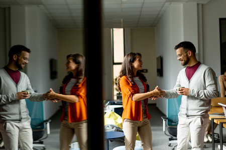 Young business couple standing and handshaking in front of her team at the modern officeの写真素材