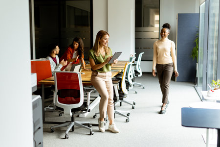 Young woman standing with digital tablet in front of her team at the modern officeの写真素材