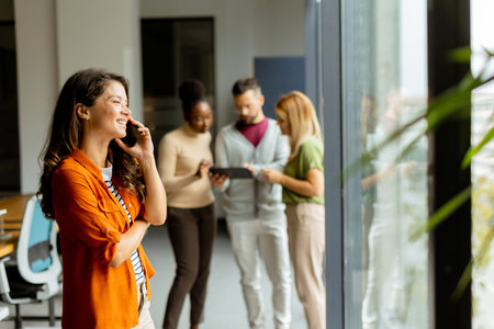 Young business woman woman with mobile phonet in front of her team at the modern officeの写真素材
