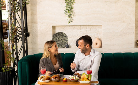 Young couple having a lunch and drinking fresh squeezed juice in the restaurantの写真素材