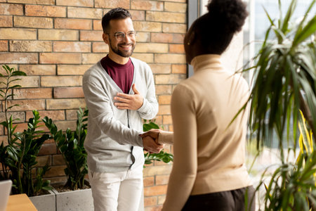 Handsome young multiethnic business couple handshaking in the modern officeの写真素材