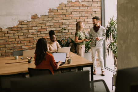 Young multiethnic startup team working by the brick wall in industrial style officeの写真素材