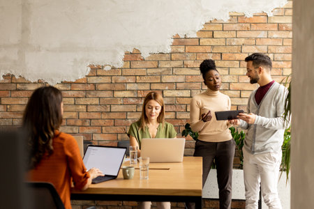 Young multiethnic startup team working by the brick wall in industrial style officeの写真素材