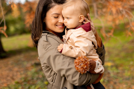Young woman holding a cute baby girl in the autumn parkの写真素材