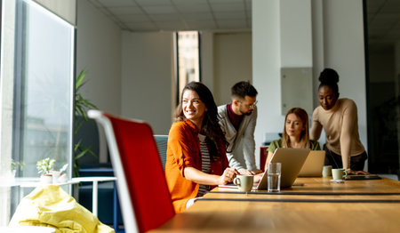 Pretty business woman working on laptop with her young multiethnic startup team working in the...
