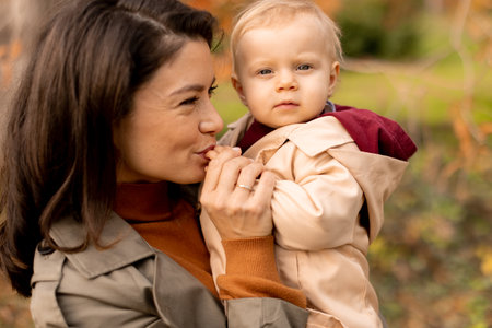 Young woman holding a cute baby girl in the autumn parkの写真素材