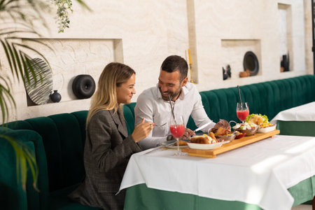 Young couple having a lunch and drinking fresh squeezed juice in the restaurantの写真素材