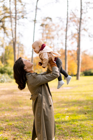 Young woman holding a cute baby girl in the autumn parkの写真素材