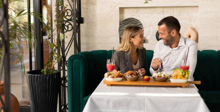 Young couple having a lunch and drinking fresh squeezed juice in the restaurantの写真素材