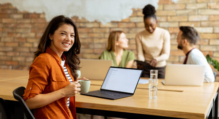 Pretty business woman working on laptop with her young multiethnic startup team working in the modern officeの写真素材