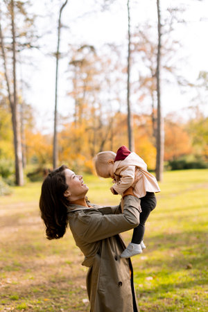 Young woman holding a cute baby girl in the autumn parkの写真素材