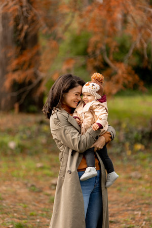 Young woman holding a cute baby girl in the autumn parkの写真素材