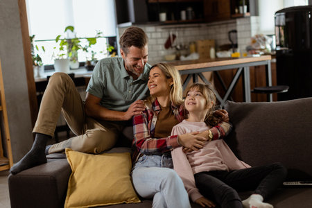Joyful family shares a relaxed, affectionate moment on the sofa, illuminated by soft natural lightの写真素材