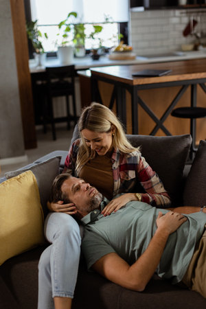 Couple shares a tender and peaceful moment as one rests their head on the others lap, surrounded by the warmth and comfort of their living room.の写真素材
