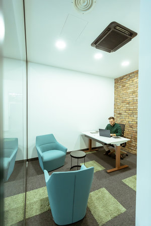 Person is immersed in a task in a stylish office with transparent glass walls. The modern design includes exposed brick, a sleek monitor, comfortable seating, and an atmosphere of quiet productivity. This scene captures a moment of dedicated work in a contemporary urban workspace.の写真素材