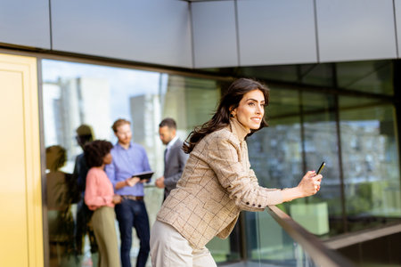 A spirited professional leads a conversation, colleagues collaborating in the background.の写真素材