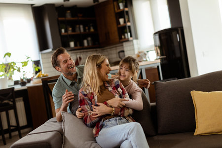 Joyful family shares a relaxed, affectionate moment on the sofa, illuminated by soft natural lightの写真素材