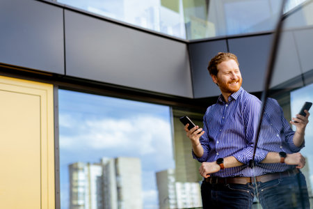 A focused man in a striped shirt talks on his phone while overlooking the balcony at bathed in sunlight.の写真素材