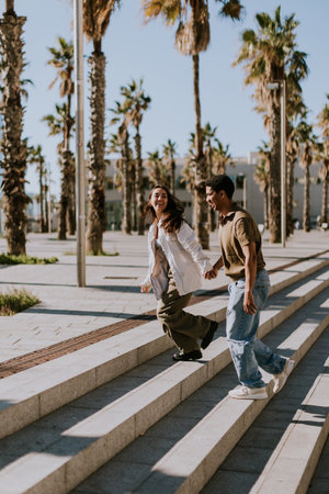 Young couple joyfully reunite on the steps of a palm-lined promenade in Barcelonas vibrant cityscapeの写真素材
