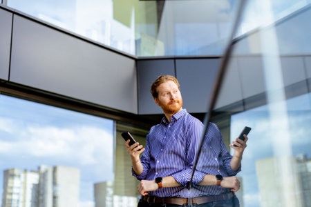 A focused man in a striped shirt talks on his phone while overlooking the balcony at bathed in sunlight.の写真素材