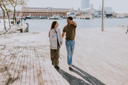 Joyful couple hugs on a pier in Barcelona, with the city skyline softly blurred in the backgroundの写真素材