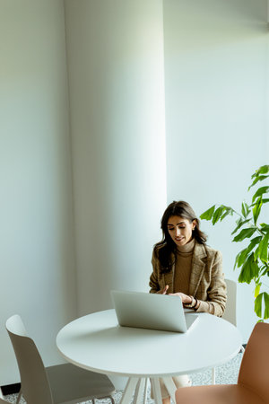 A professional woman focused on her work at a laptop in a chic, sunlit cafÃ©.の写真素材