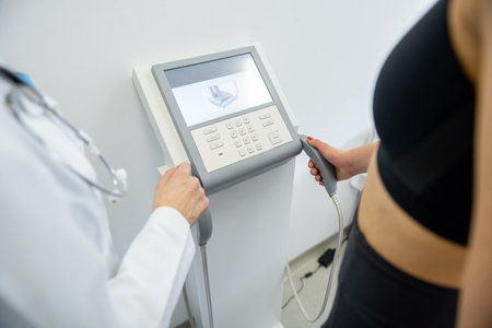 A health practitioner assists a woman with a body composition test using advanced equipment.の写真素材