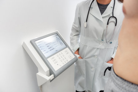 A doctor in a white coat uses a modern medical device to perform a health checkup.の写真素材