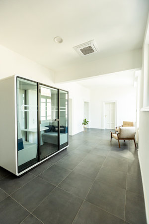 Contemporary office with large glass meeting room, minimalist furniture, and bright ambianceの写真素材