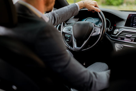 Joyful driver smiles while holding the wheel, cruising down the road in a well-equipped vehicleの写真素材
