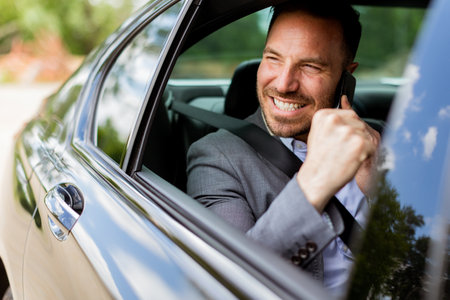 Man chuckles merrily during a car ride, enjoying a lively conversation on his mobile phone