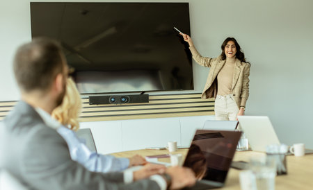 Poised woman presents to colleagues during a meeting, her expression conveying enthusiasm and leadershipの写真素材