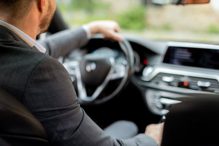 Suited man confidently steers his modern luxury vehicle through the city streets as evening falls