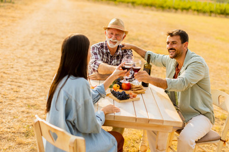 Amidst rows of lush vines, three friends enjoy a delightful afternoon, savoring wine and conversation, surrounded by the beauty of natureâs harvestの写真素材