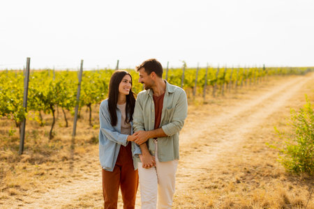 Joyful couple shares laughter and embraces under the warm sun in a picturesque vineyard, framed by rows of vibrant grapevines and golden earthの写真素材
