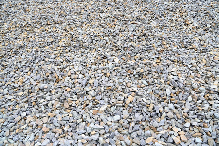 Vast expanse of crushed stone fills the ground at a construction site, with varied shades of gray and natural hues intermingling harmoniously under daylightの写真素材