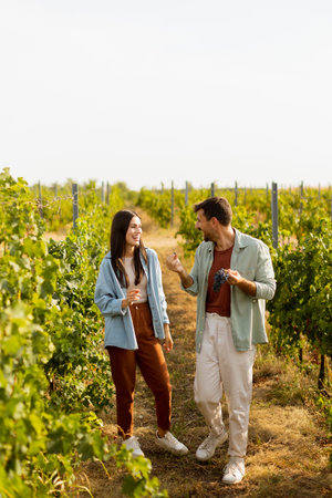 Young couple walks together through lush vineyards, sharing smiles and laughter as they immerse themselves in a delightful afternoon amidst the vinesの写真素材