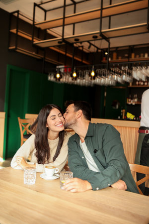 Two friends share laughter and warm drinks at a charming cafe, creating an inviting atmosphere that celebrates connection and joy during a sunny dayの写真素材