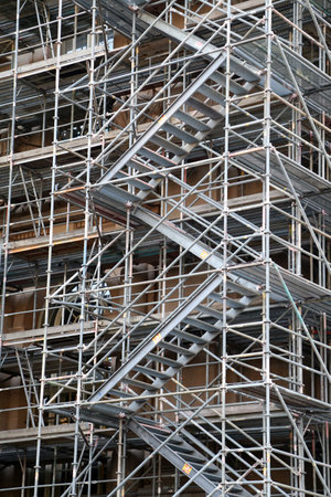 Sturdy steel staircase winds through a complex grid of scaffolding, illustrating the active construction process and the intricate support systems in place for building projectsの写真素材