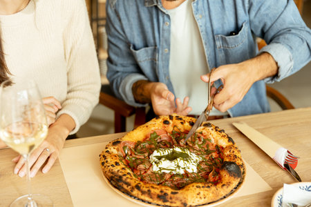 A man and woman sit at a wooden table in a welcoming restaurant, smiling as they share a tasty pizza...