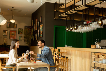 A couple engages in lively conversation while savoring delicious cuisine at a bright restaurant, sharing laughter and moments of connection over a leisurely meal.の写真素材